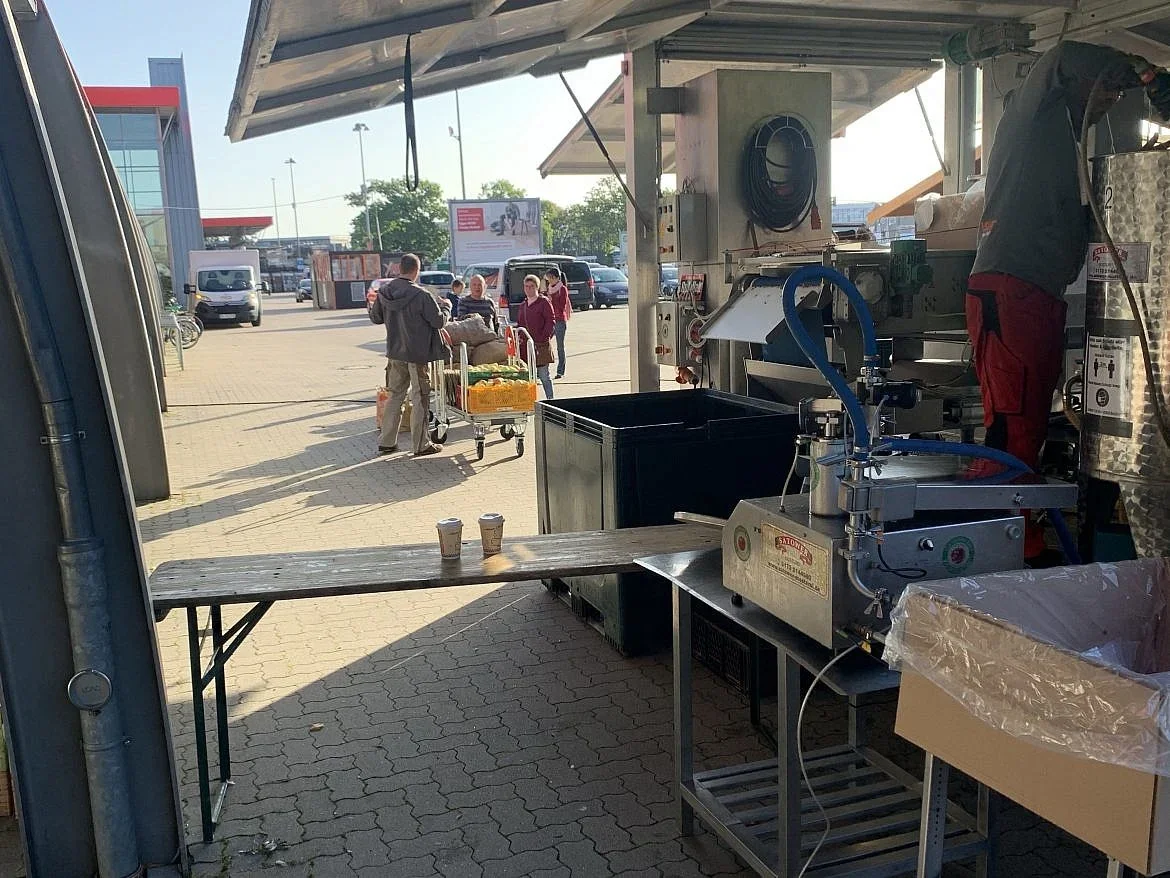 Mobile Saftpresse im Einsatz, im Hintergrund Kundschaft mit Bollerwagen