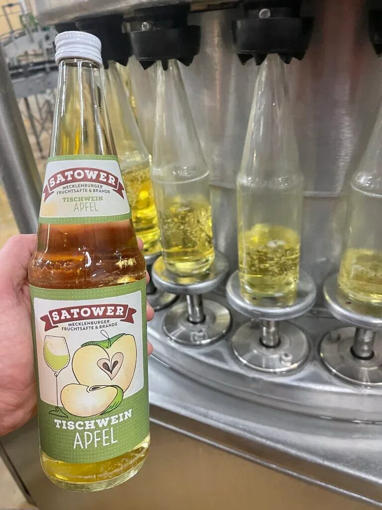 Flasche Apfel-Tischwein mit neuem Etikett vor der Abfüllanlage
