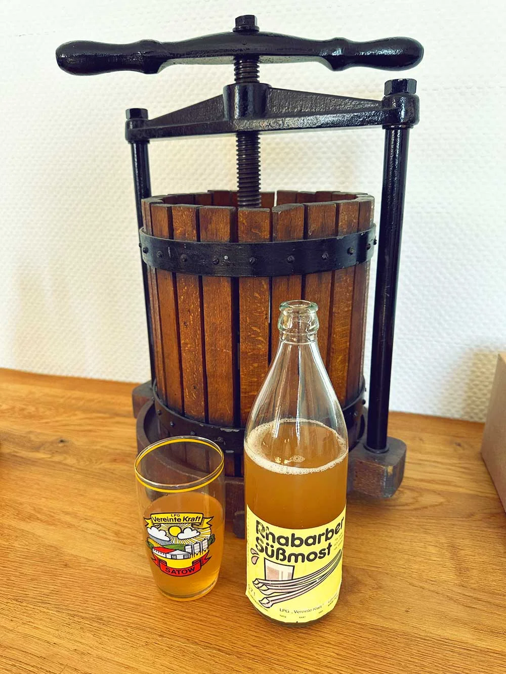 Alte Obstpresse mit Flasche und Glas Rhabarber-Süßmost