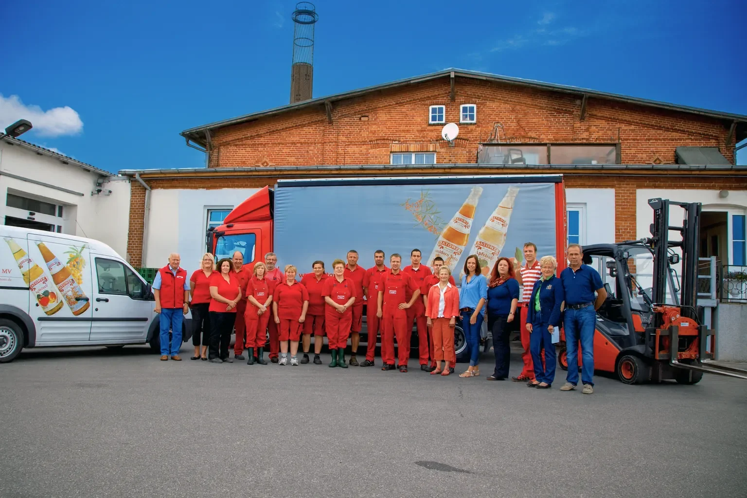Das Team der Satower Mosterei vor dem Betriebsgebäude in Satow, mit Lieferwagen und Lkw
